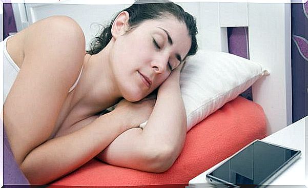 A woman is sleeping with a tablet next to her head