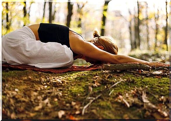 A woman is practicing yoga in the forest