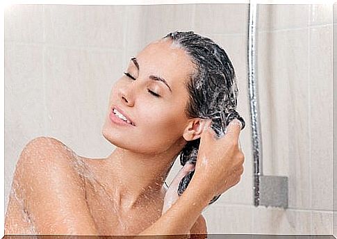 The woman washes her hair in the shower