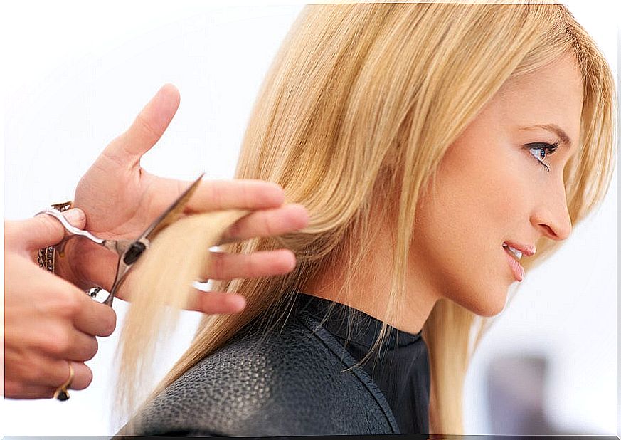 The hairdresser cuts the woman's hair