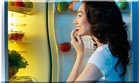 Snacking eating habits, the woman looks at the refrigerator